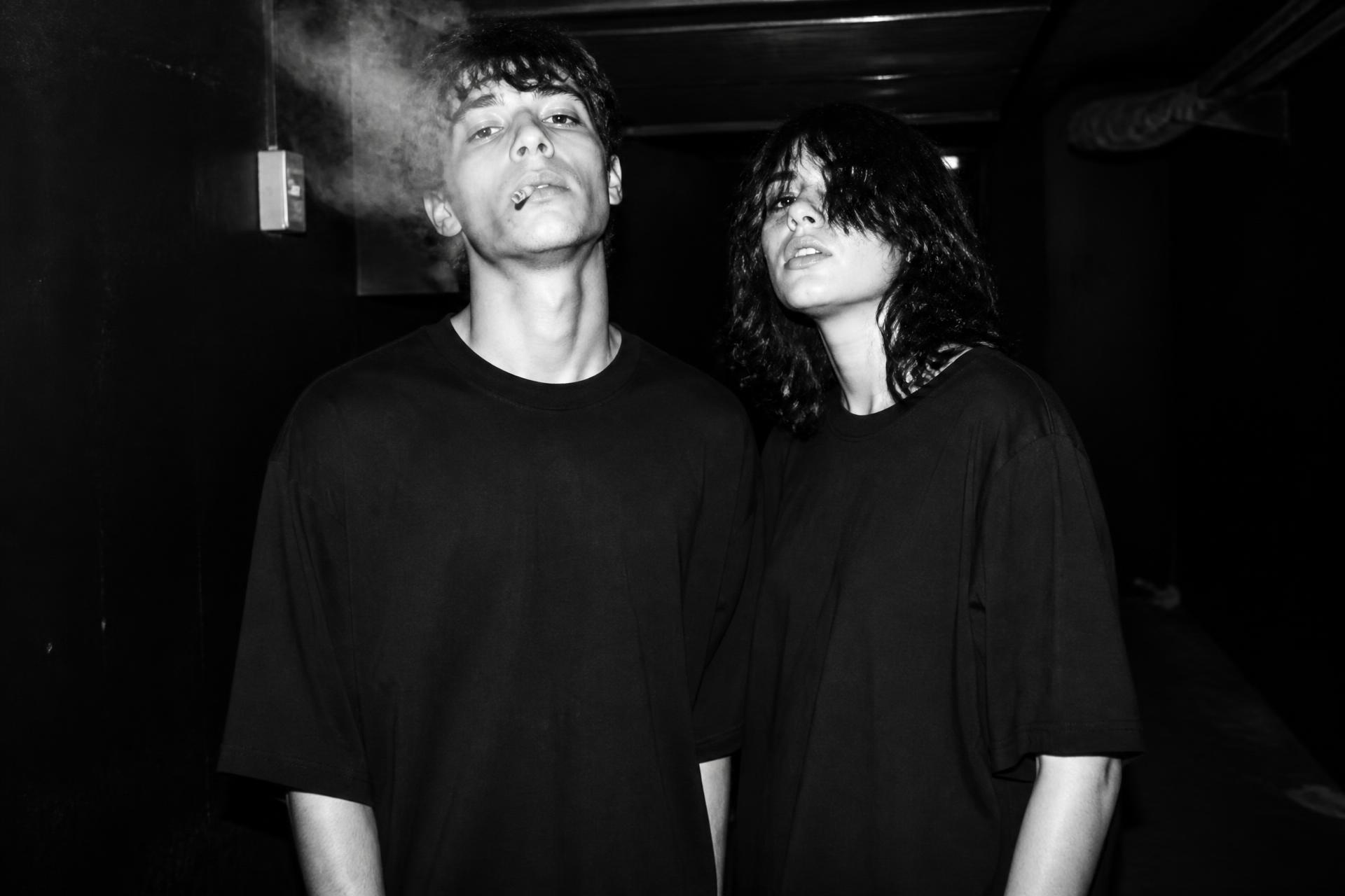 WFL campaign: two people in oversized black tees in a dark club corridor